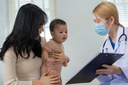 Pediatric consultation with doctor, parent, and baby in a medical settingの写真素材