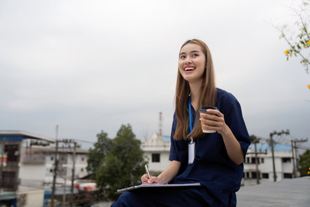 Nurse enjoying a break with coffee while taking notes for patient careの写真素材
