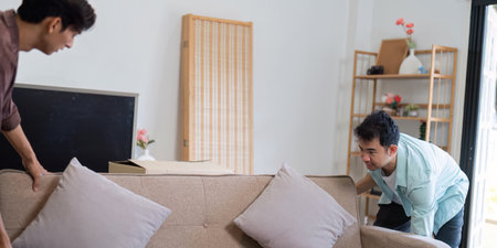 LGBT couple arranging their new sofa with smiles and teamwork in the living roomの写真素材
