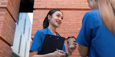 Healthcare professionals conversing during a break with coffee and clipboardの写真素材