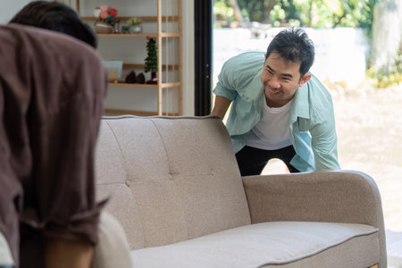 Happy couple moving house with a stylish sofa in a modern living roomの写真素材
