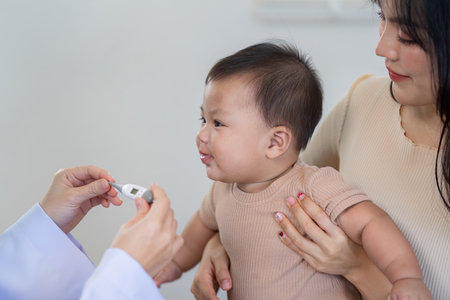 Baby reacting to temperature measurement by pediatrician in clinic.の写真素材