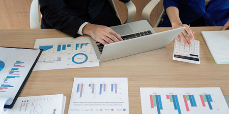 Focused business team analyzing data reports and collaborating on insights in a modern workspace.の写真素材