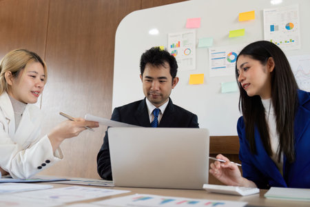 Collaborative business team discussing analysis and sharing reports during a strategy meeting in a modern office.の写真素材