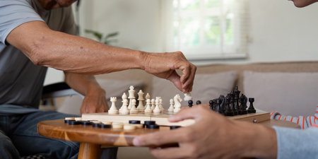 Close-up of father making a chess move while son focuses on the game.