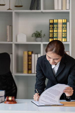 Female lawyer reviewing legal documents in a law office with books and gavel.の写真素材