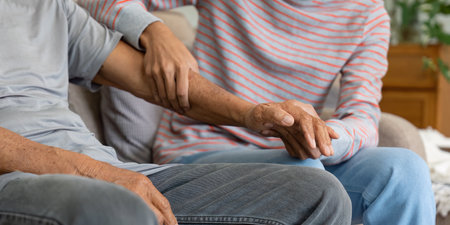 Tender moment of son holding elderly father's hand, symbolizing love and support in a family...