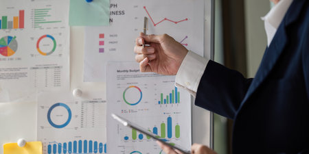 Elderly businessman presenting financial charts and graphs during a meeting.