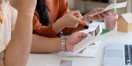 Couple discussing financial planning and managing bills with calculator and documents.の写真素材