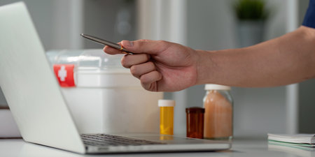 Healthcare professional managing medication and technology in a modern workspace, illustrating contemporary medical practices.の写真素材