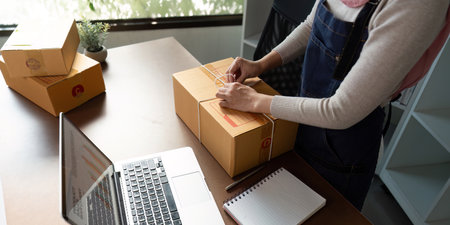 Muslim entrepreneur sealing a package for online sale, showcasing dedication to her business in a...