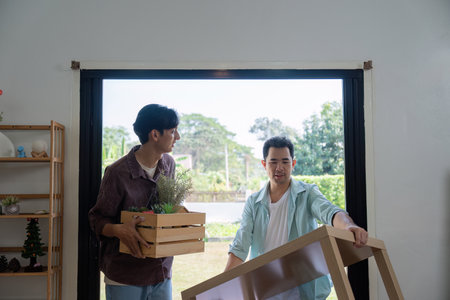 Gay couple carrying boxes and plants while moving into their new house.の写真素材