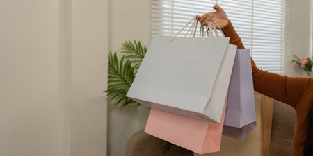 Happy shopper holding colorful bags and a credit card, celebrating online shopping success.の写真素材