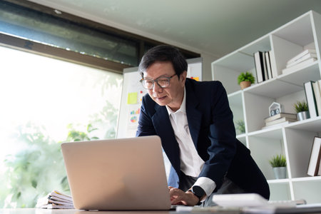 Elderly financial analyst presenting budget insights in a contemporary office setting.の写真素材