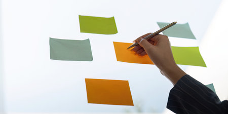 Colleagues sharing insights while arranging sticky notes for project planning and analysis.の写真素材