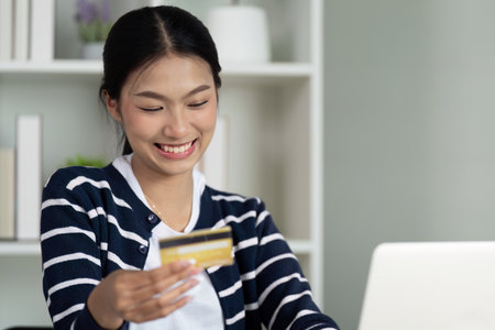 Happy woman holding credit card while managing online finances