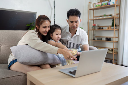 Family sharing a cozy moment while watching a movie togetherの写真素材
