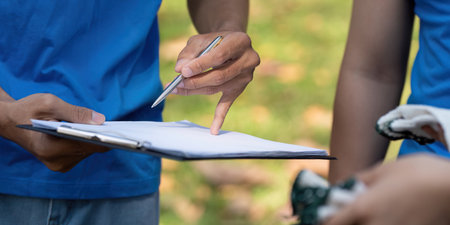 Volunteers discussing plans during a community clean-up event, promoting sustainability and teamwork.の写真素材