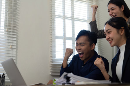 Celebrating success, a team rejoices after overcoming project challenges in the office.の写真素材