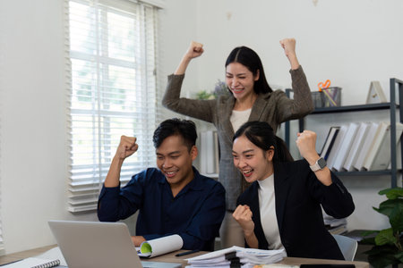 Team celebrating success in a modern office, showcasing enthusiasm and teamwork.の写真素材