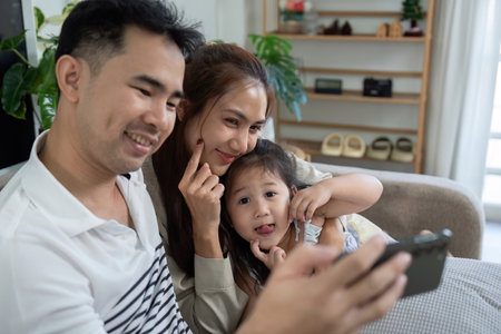 Playful family enjoying fun moments together with a smartphoneの写真素材