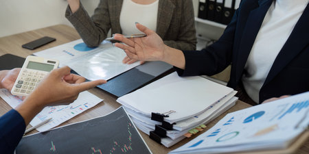 Analytical teamwork. Colleagues discussing tax data and financial strategies in a collaborative workspace.の写真素材