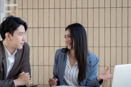 Professional collaboration. Two business professionals engaging in a discussion while analyzing project plans and strategies.の写真素材