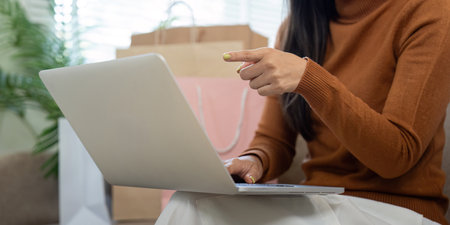 Shopping enthusiasm. Woman excited about online shopping while using credit card and laptop in her stylish living room.の写真素材