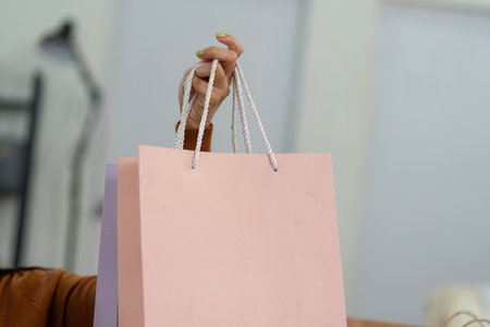 Online shopping experience. Woman shopping online with laptop in cozy living room with shopping bags.の写真素材
