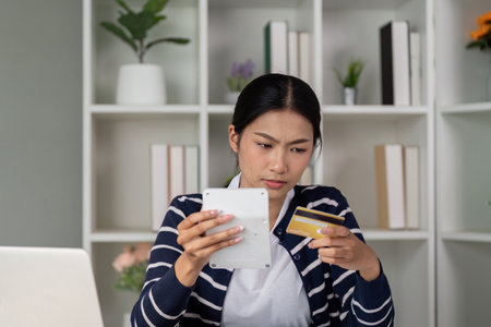 Concerned woman checking credit card details while managing finances.の写真素材