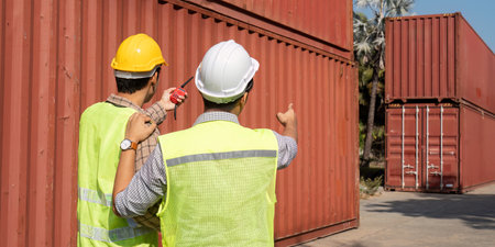 Team collaboration. Engineers discussing logistics at a shipping container site.