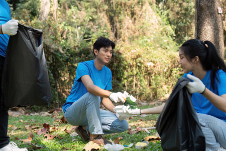 Collaboration for a cleaner environment. Volunteers exchanging waste during a park cleanup.の写真素材