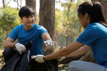 Team Collaboration and Environmental Care. A young man and woman cooperate in a sustainability project, collecting waste to enhance the local ecosystem.の写真素材