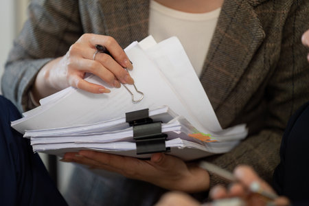 Organization and Documentation. A woman managing a stack of documents, ensuring effective organization and clarity.の写真素材