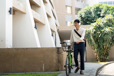 Biking and Lifestyle. A young man walking his bicycle through an urban area, embracing an active and sustainable lifestyle.の写真素材