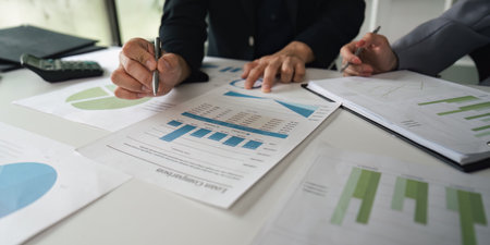 Analysis and Data Review. Close-up of colleagues reviewing financial reports and graphs together.の写真素材