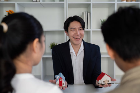 Real Estate Consultation and Client Interaction. A real estate agent presents two models to a couple during their consultation.の写真素材