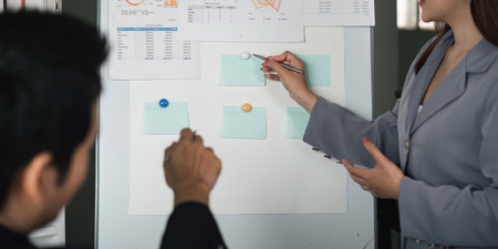 Data Analysis and Strategy. A focused discussion on performance metrics using visual aids during a team meeting.の写真素材