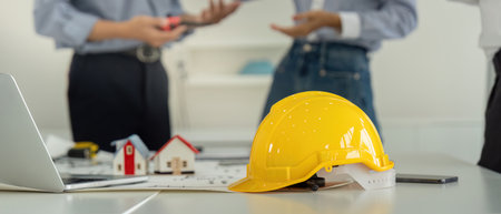 Project Discussion and Safety Gear. A construction helmet symbolizing safety during planning...