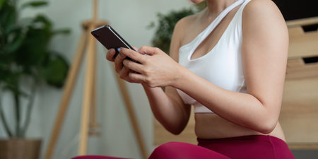 Yoga and Mindfulness. A woman engaging in yoga practice while checking her phone for guidance.の写真素材