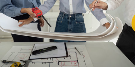 Teamwork and Project Discussion. Professionals examining detailed construction plans while focused on efficient building design.の写真素材