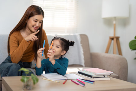 Creative Learning and Family Interaction. A mother and daughter engage in fun activities with art supplies.の写真素材