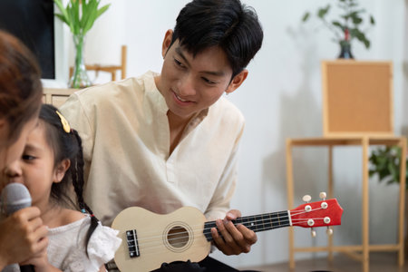 Family Harmony and Music Education. A father enjoying playful music time while watching his daughter sing.の写真素材