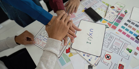 Collaboration and UX UI Design. Team members unite hands over design concepts, emphasizing teamwork...