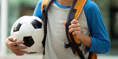 Mother and Son Bonding Over Soccer. A young boy excitedly holding a soccer ball while attending...