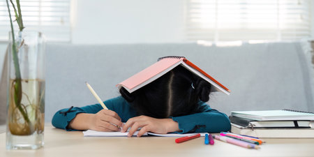 Education and Stress Management. A young girl feeling overwhelmed while studying at home.の写真素材