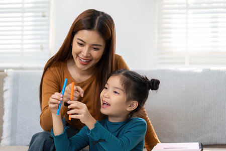 Creativity and Connection. A mother and daughter share colorful pens during an educational moment.の写真素材