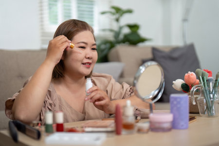 Beauty and Facial Care. A woman applying serum with focus in her bright beauty space.の写真素材