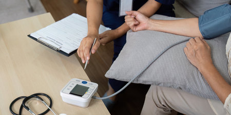Health Monitoring and Caregiving. A caregiver measuring blood pressure of an elderly patient at...