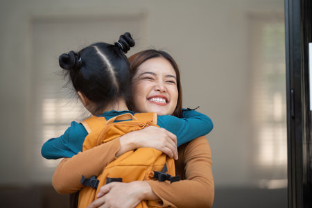 Warm Hugs and Happy Returns. A mother embraces her daughter after school, celebrating her arrival.の写真素材